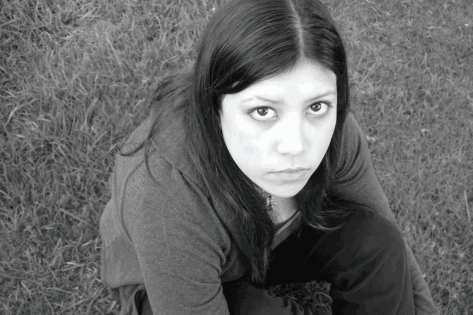 bw image of a girl sitting in the grass looking at camera